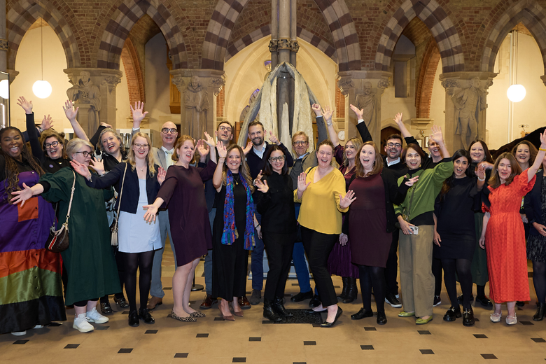 26 adults from the 2025 OCL cohort stood in front of a whale's jaw bone at the Oxford University Museum of Natural History