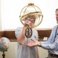 Staff showing student an astrolabe