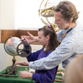 Staff showing student how to use an astrolabe