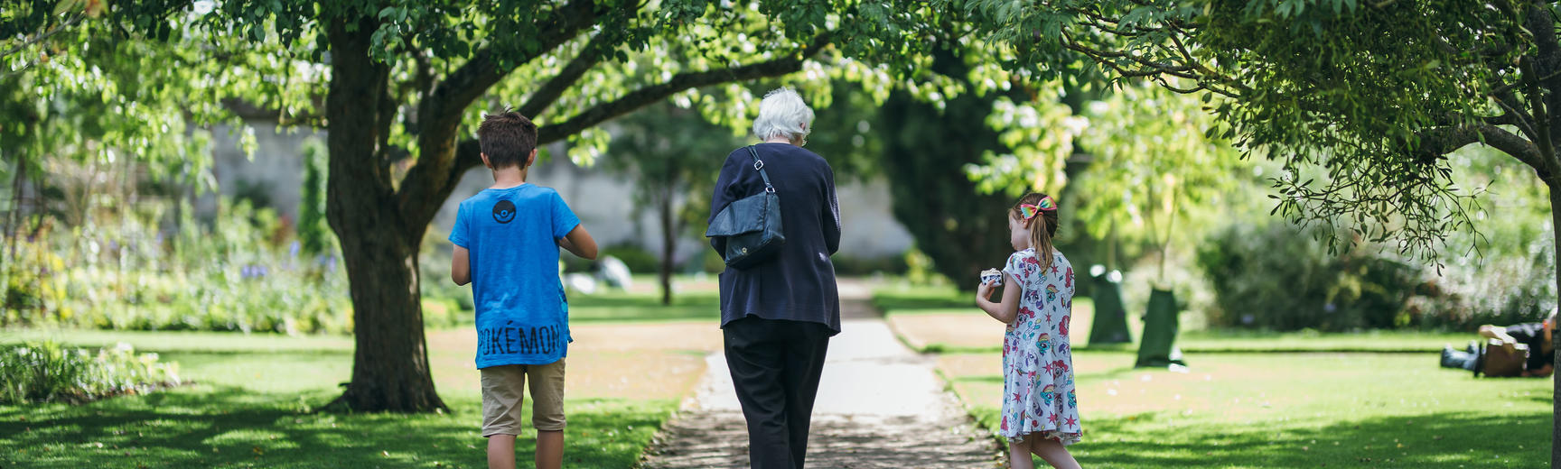 Two children and grandparent walking in botanic garden