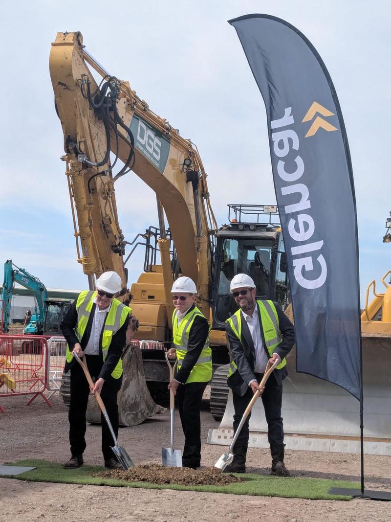 Three suited men use ornamental shovels to move a small pile of earth. 