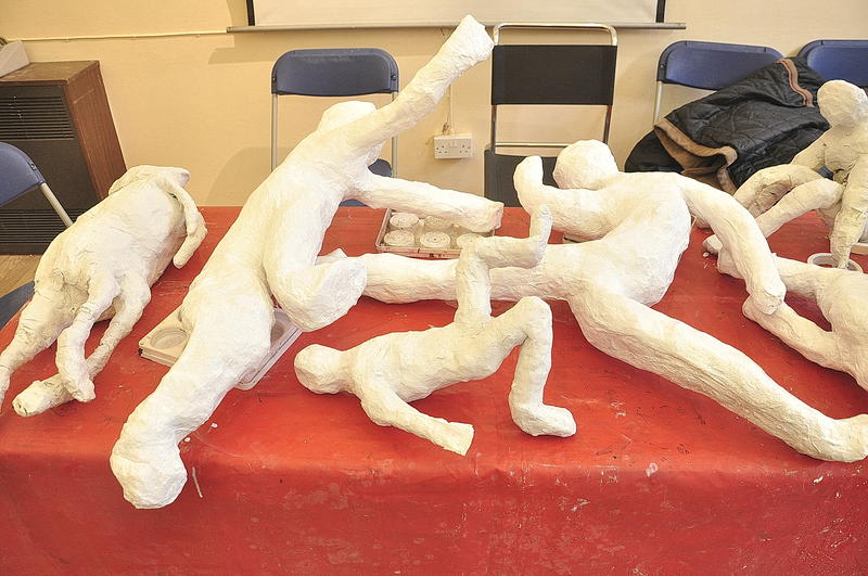 Plaster sculptures of Olympic athletes in different poses on a red table cloth