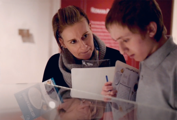 Museum staff and school student looking at museum case