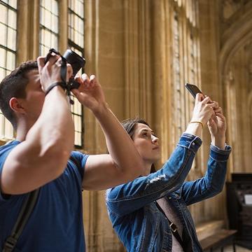 Two visitors taking photos of the Divinity School