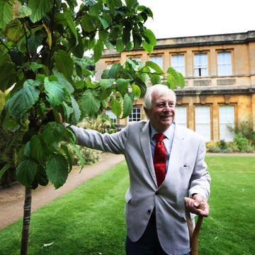 Chancellor Chris Patten stands beside a tree he has just planted
